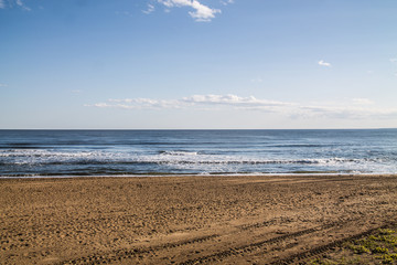 sea coast view with waves, sand beach and blue sky