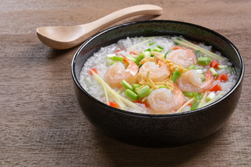 close up of boiled rice clear soup with shrimp in a ceramic bowl on wooden table. asian homemade style food concept.