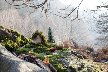 Christmas and New Year miniature house at forest in the sunlight. Little toy house close up. Festive background. Christmas decorations. Holiday and celebration concept.