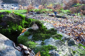 Christmas and New Year miniature house at forest in the sunlight. Little toy house close up. Festive background. Christmas decorations. Holiday and celebration concept.