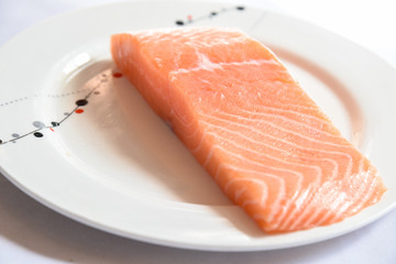 Salmon in white dish on white blackground.