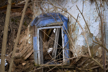 Abandoned dilapidated house in the winter forest. Old wooden windows with preserved decorative...