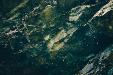 Dark green rocky surface with cobweb in cave in darkness close-up. Atmospheric horror background with copy space. Creepy shadows in scary dungeon. Terrible dark place in deep cave. Fear of spiders.