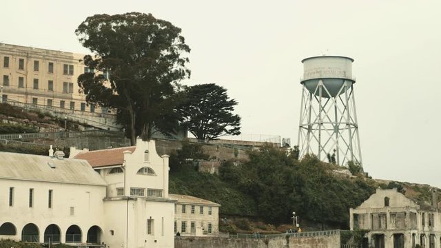 Alcatraz prison water reservoir and buildings - handheld shot with long lens from ferry, San Francisco, USA