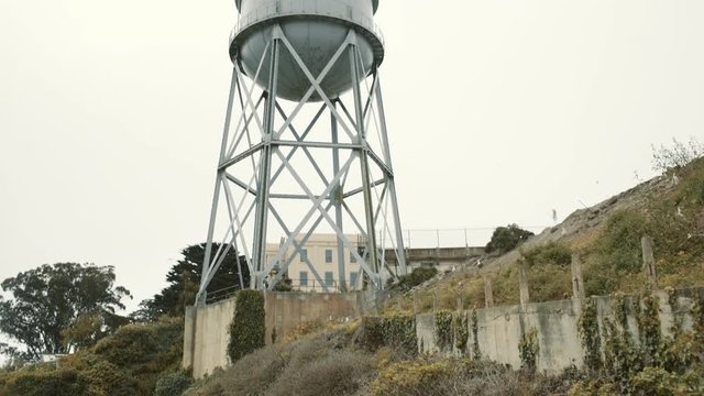 Wide tilt up revealing shot of water reservoir and flying seagulls in sky on Alcatraz island, San Francisco, USA