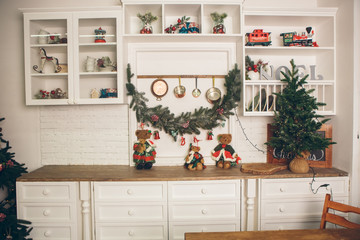 Interior light kitchen and red christmas decor. Preparing holiday dinner at home on the kitchen concept. Decorated new Year fir. 