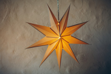 Lantern christmas stars hanging in front of a brick wall