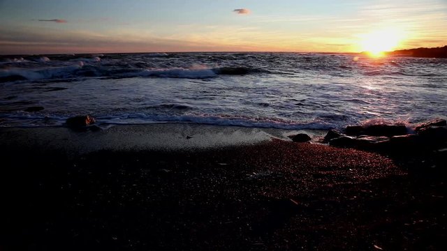 Atlantic Ocean waters wash up upon the shore in Cape Cod during a beautiful sunset.