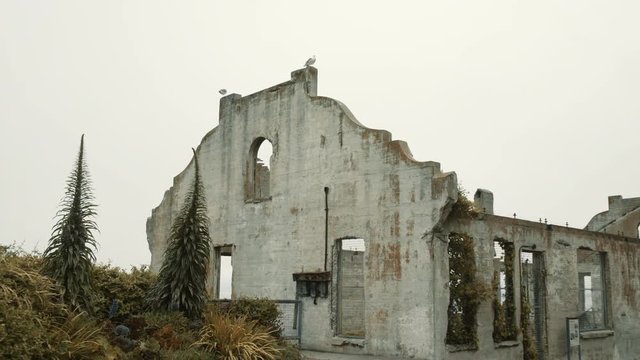 Moving towards historical concrete building on Alcatraz island, with bushes on side, San Francisco, USA