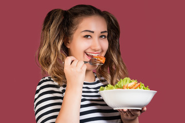 Portrait of a girl with bowl of fresh salad looking at camera
