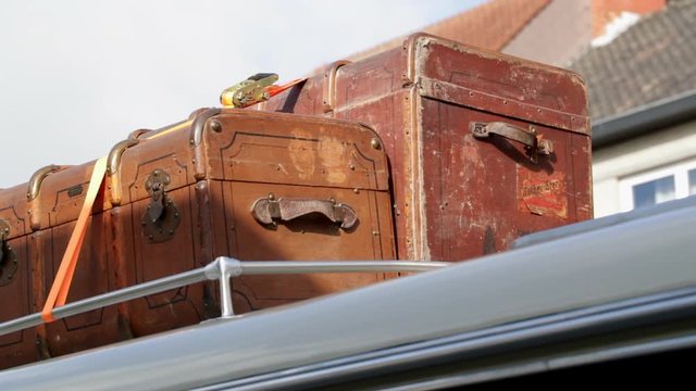 2 old vintage suitcases fastened together on top of an oldtimer bus coach.