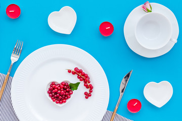 Empty white colorful plate and wineberry for table setting on blue table backgroung top view