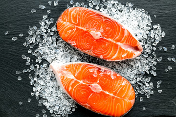 Raw salmon fish on black plates for cooking steaks. Restaurant kitchen background top view