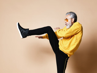 Old brutal senior millionaire man make a punch hit with leg in aviator sunglasses stylish fashionable men