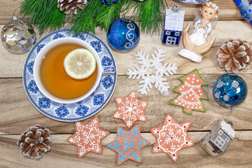 New Year's table with fir branches and decorations on a wooden background. Christmas tea with cookies, gingerbread, small stars. Festive background in blue tones.