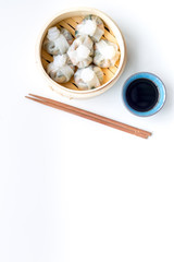 Dinner in Chinese restaurant with dim sum, sticks and tea on white background top view space for text