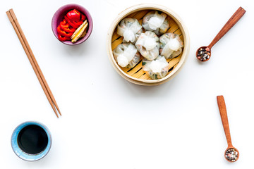 Chinese food set with dim sum, sticks and tea on white background top view copy space