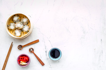 Dim sums with red pepper and vegetables with sticks and black tea in Chinese restaurant on marble background top view mockup