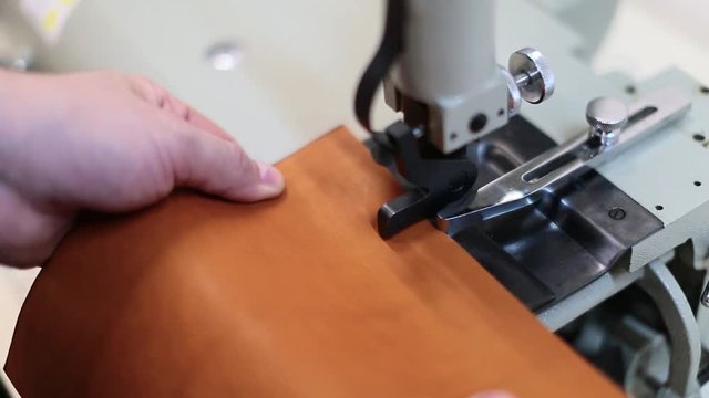close up view of a process of making leather craftwork. Worker using skiving machine