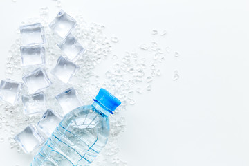 Bar desk with ice cubes and plastic bottle on white background top view space for text