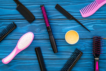 female hairdresser desk with accessories and combs on blue wooden background top view
