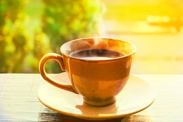 A cup of black coffee. Hot with steam. Sunny warm day