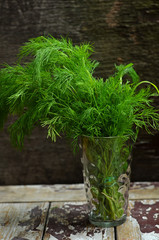 Fresh dill in a glass on a wooden background