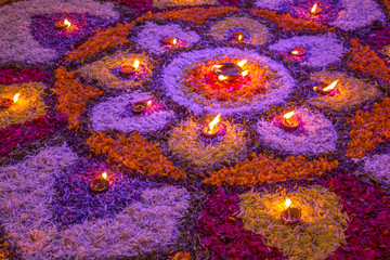 big mandala of colorful fresh flower petals, with burning candles at night on the diwali festival