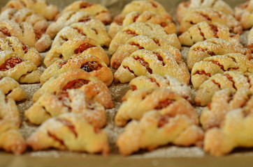 Freshly baked croissants with jam sprinkled with powdered sugar on baking paper