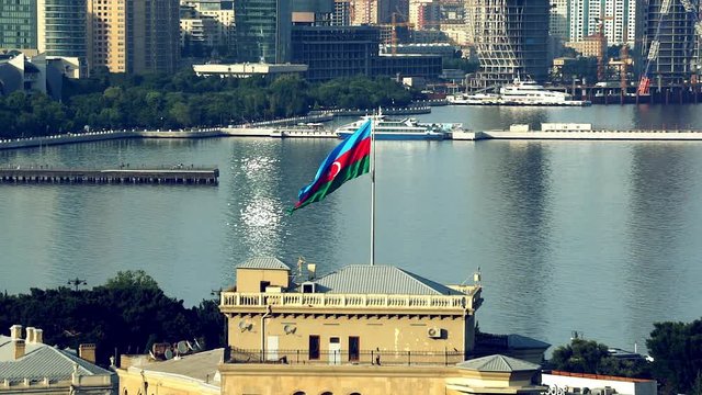 Baku cityscape with national flag of Azerbaijan on flagpole. Medium shot .