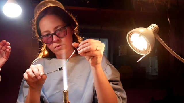 Young Woman Student Learning to Apply Molten Glass Dots to Handmade Beads While Beadmaking