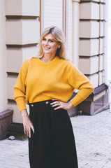 An elegant girl in a yellow loose sweater and a black skirt. Portrait. Smiling girl. Clothes in style oversize