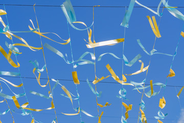festive background - blue and golden satin ribbons against blue sky.