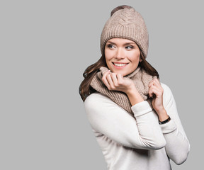 Beautiful woman looking away. Isolated on grey background. Smiling girl wearing warm clothes, winter portrait