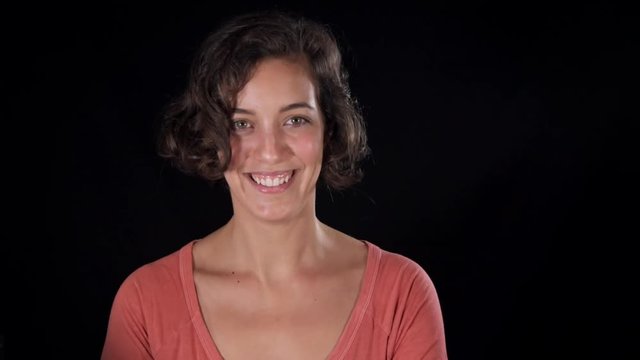 Adorable young woman, isolated on a black studio background, pouting and posing in an ironic and funny way