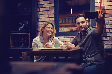Attractive couple taking selfie while having a cup of coffee.