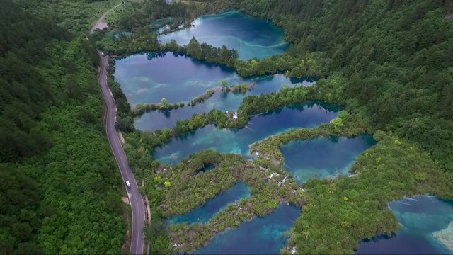 Superb aerial shot over a long road and bodies of water partitioned by trees and plant life