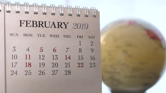 Motion of February 2019 calendar with blur earth globe turning background