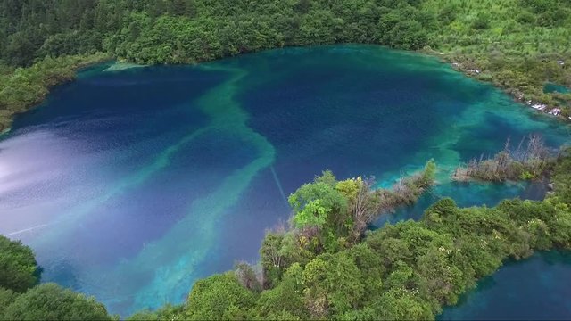 Mesmerizing aerial shot of a big beautiful multi coloured lake in a secluded mountainous region