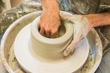     Artist potter in the workshop creating a jug out of earthenware, hands closeup. Twisted...