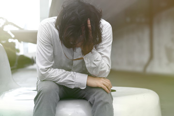 Anxiety tired Asian business man covering face with hands.