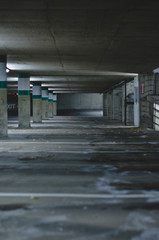 The long and empty salt covered parking stalls in the dark parking garage in the late night. 