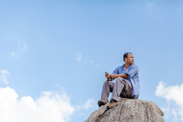 a man sitting on rock  with blue sky background