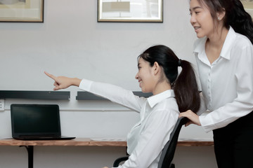Two playful young Asian business woman playing together with chair in office.