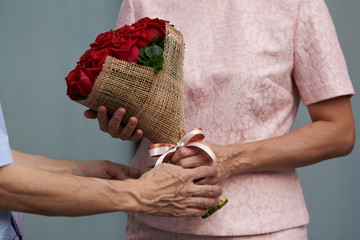 A man giving a bouquet of roses to a woman