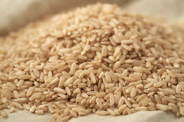 Macro photo of brown rice on a linen tablecloth background. Close up of brown rice.