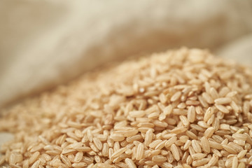 Macro photo of brown rice on a linen tablecloth background. Close up of brown rice.