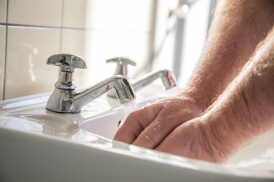 Mann nutzt Waschbecken mit Leitungswasser zum H&auml;ndewaschen