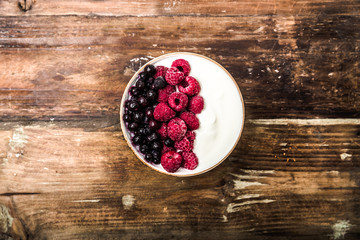 Raspberries and blueberries in a Bowl. Healthy breakfast concept with yoghurt and muesli
