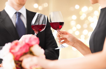celebration, drinks and alcohol concept - hands of couple clinking red wine glasses